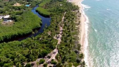 Tropikal beyaz kumlu plaj ve küçük dalgalar ve palmiye ağaçları ormanı ile turkuaz berrak deniz suyu havadan görünümü. Praia do Forte, Bahia, Brezilya. Seyahat tropikal kavramı