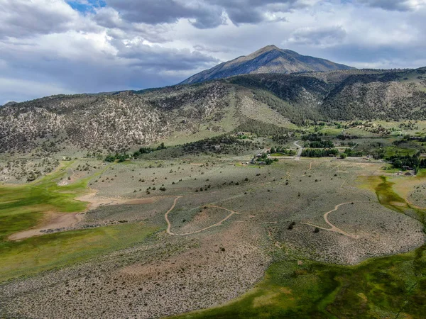 Aerial top view of green land and mountain in the background in Aspen Springs, Mono County California, USA