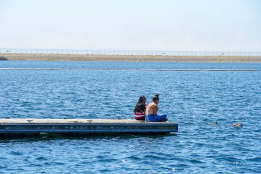 Arkadaşlar mutluluk. Yong kızlar ahşap iskelede oturan ve bir dinlenme zaman yaşıyorsanız. Miramare Gölü, San Diego, Kaliforniya, Amerika Birleşik Devletleri.