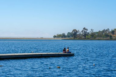 Arkadaşlar mutluluk. Yong kızlar ahşap iskelede oturan ve bir dinlenme zaman yaşıyorsanız. Miramare Gölü, San Diego, Kaliforniya, Amerika Birleşik Devletleri.