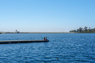 Arkadaşlar mutluluk. Yong kızlar ahşap iskelede oturan ve bir dinlenme zaman yaşıyorsanız. Miramare Gölü, San Diego, Kaliforniya, Amerika Birleşik Devletleri.