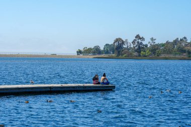 Arkadaşlar mutluluk. Yong kızlar ahşap iskelede oturan ve bir dinlenme zaman yaşıyorsanız. Miramare Gölü, San Diego, Kaliforniya, Amerika Birleşik Devletleri.