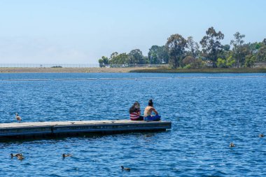 Arkadaşlar mutluluk. Yong kızlar ahşap iskelede oturan ve bir dinlenme zaman yaşıyorsanız. Miramare Gölü, San Diego, Kaliforniya, Amerika Birleşik Devletleri.