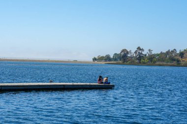 Arkadaşlar mutluluk. Yong kızlar ahşap iskelede oturan ve bir dinlenme zaman yaşıyorsanız. Miramare Gölü, San Diego, Kaliforniya, Amerika Birleşik Devletleri.