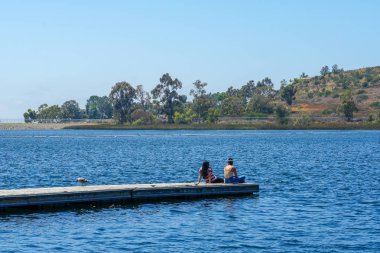 Arkadaşlar mutluluk. Yong kızlar ahşap iskelede oturan ve bir dinlenme zaman yaşıyorsanız. Miramare Gölü, San Diego, Kaliforniya, Amerika Birleşik Devletleri.