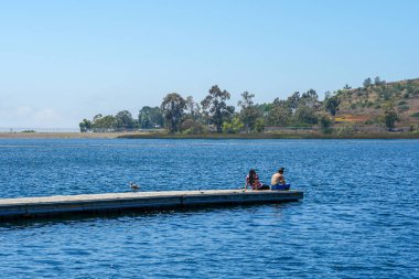 Arkadaşlar mutluluk. Yong kızlar ahşap iskelede oturan ve bir dinlenme zaman yaşıyorsanız. Miramare Gölü, San Diego, Kaliforniya, Amerika Birleşik Devletleri.