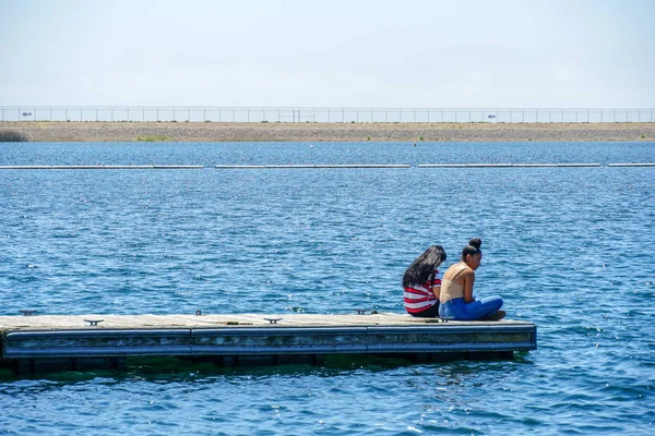 Arkadaşlar mutluluk. Yong kızlar ahşap iskelede oturan ve bir dinlenme zaman yaşıyorsanız. Miramare Gölü, San Diego, Kaliforniya, Amerika Birleşik Devletleri.
