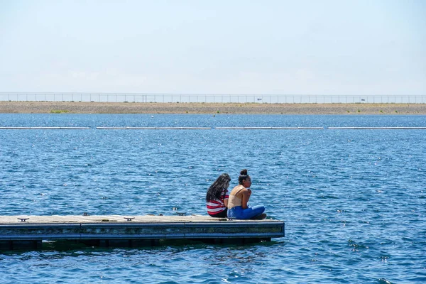 Arkadaşlar mutluluk. Yong kızlar ahşap iskelede oturan ve bir dinlenme zaman yaşıyorsanız. Miramare Gölü, San Diego, Kaliforniya, Amerika Birleşik Devletleri.