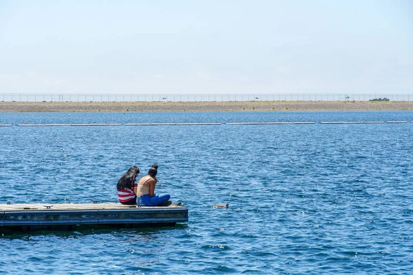 Arkadaşlar mutluluk. Yong kızlar ahşap iskelede oturan ve bir dinlenme zaman yaşıyorsanız. Miramare Gölü, San Diego, Kaliforniya, Amerika Birleşik Devletleri.