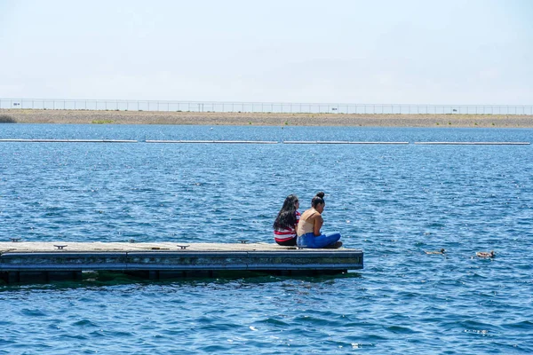 Arkadaşlar mutluluk. Yong kızlar ahşap iskelede oturan ve bir dinlenme zaman yaşıyorsanız. Miramare Gölü, San Diego, Kaliforniya, Amerika Birleşik Devletleri.