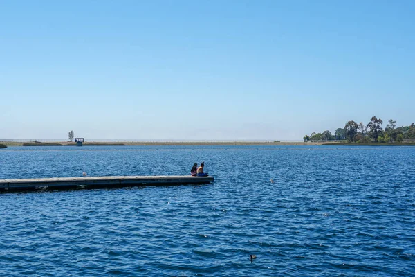 Arkadaşlar mutluluk. Yong kızlar ahşap iskelede oturan ve bir dinlenme zaman yaşıyorsanız. Miramare Gölü, San Diego, Kaliforniya, Amerika Birleşik Devletleri.