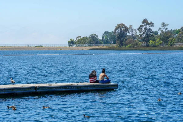 Arkadaşlar mutluluk. Yong kızlar ahşap iskelede oturan ve bir dinlenme zaman yaşıyorsanız. Miramare Gölü, San Diego, Kaliforniya, Amerika Birleşik Devletleri.