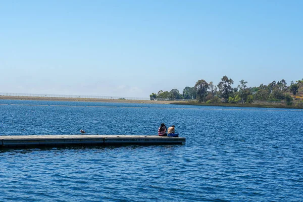 Arkadaşlar mutluluk. Yong kızlar ahşap iskelede oturan ve bir dinlenme zaman yaşıyorsanız. Miramare Gölü, San Diego, Kaliforniya, Amerika Birleşik Devletleri.