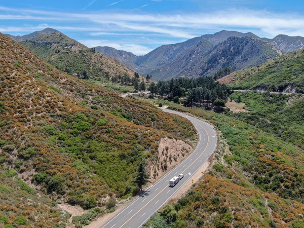 Asphalt road bends through Angeles National forests mountain, California, USA.Thin road winds between a ridge of hills and mountains at high altitude