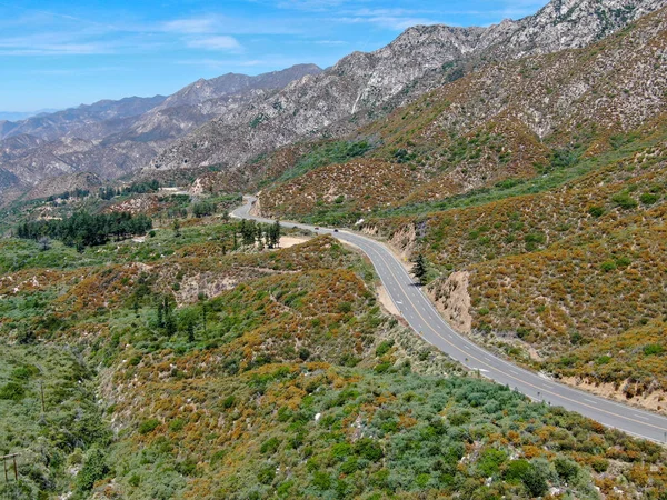 Asphalt road bends through Angeles National forests mountain, California, USA.Thin road winds between a ridge of hills and mountains at high altitude