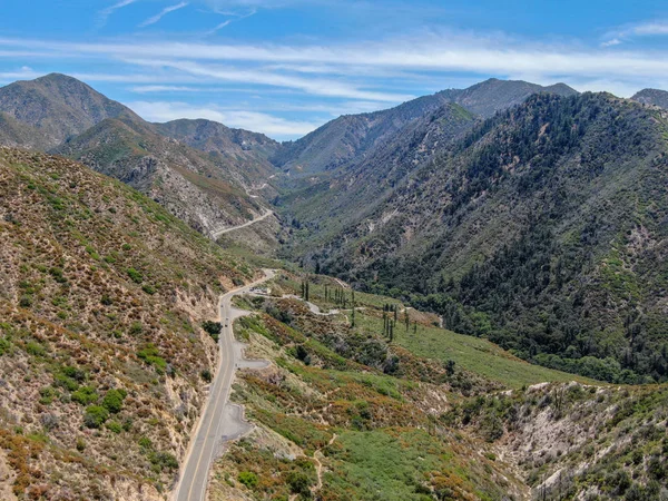 Asphalt road bends through Angeles National forests mountain, California, USA.Thin road winds between a ridge of hills and mountains at high altitude