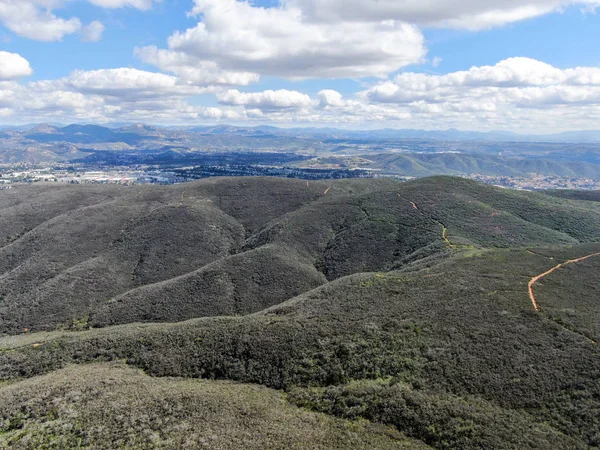 Aerial view of Black Mountain in Carmel Valley, San Diego, California, USA. Green dry mountain during sunny cloudy day with hiking trails, perfect for sport activity an leisure time..