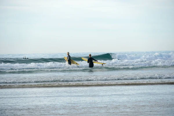 Surferova Dvojice Mokrém Obleku Držící Pláži Žlutý Surboard Surfaři Jdou — Stock fotografie