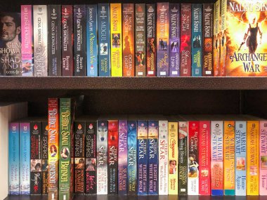 Kitapçıdaki raflarda sıralar dolusu kitap var.