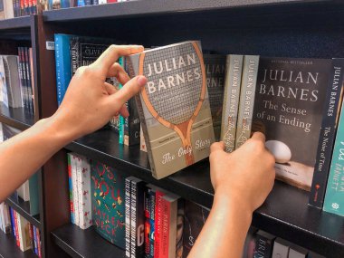 Kitapçıda elleri kitap tutuyor..