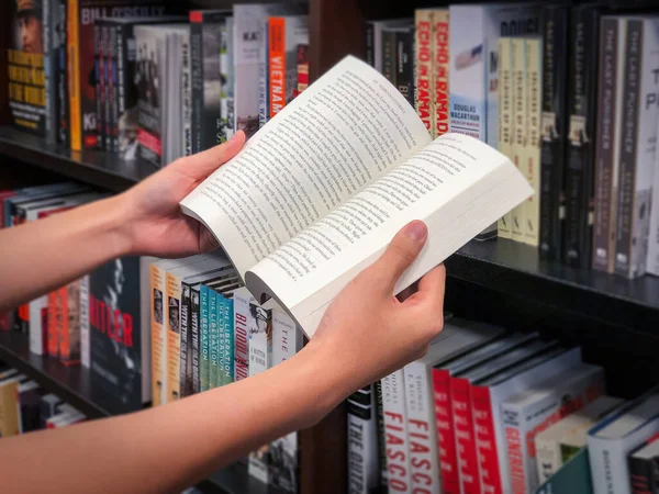 Руки тримають книгу в книжковому магазині.. — стокове фото