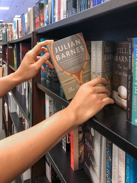 Manos sosteniendo un libro en la librería . — Foto de Stock