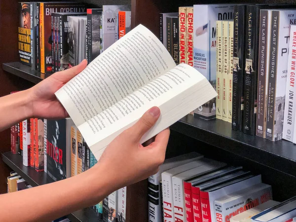 Hands holding a book at book store. — Stock Photo, Image