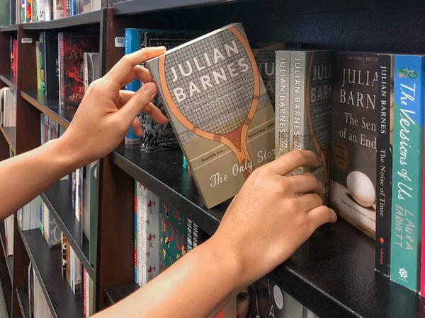 Manos sosteniendo un libro en la librería . — Foto de Stock