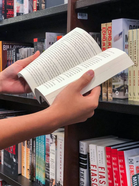 Händerna håller en bok i bokhandeln. — Stockfoto