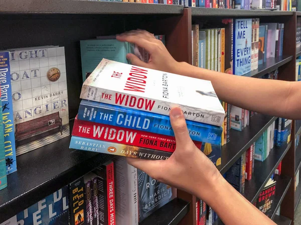 Manos sosteniendo un libro en la librería . — Foto de Stock