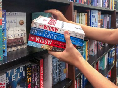 Kitapçıda elleri kitap tutuyor..