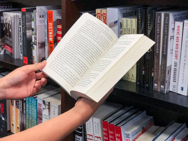 Händerna håller en bok i bokhandeln. — Stockfoto