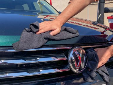 Adam elleri mikrofiber bezle arabayı temizliyor..