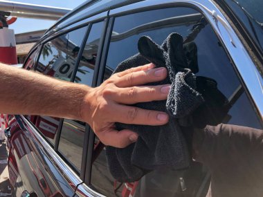 Adam elleri mikrofiber bezle arabayı temizliyor..