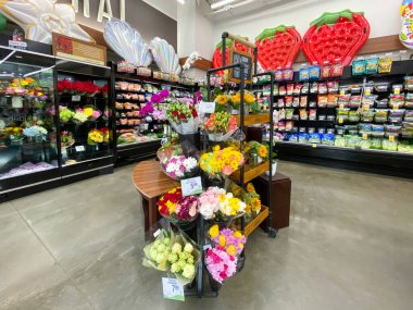 Çiçek reyonlu ve rafları çeşitli ürünlerle dolu bir süpermarketin iç görünümü