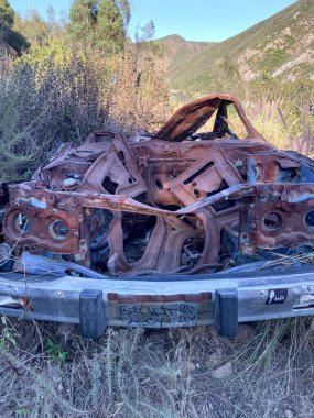 Mavi gökyüzüne karşı dağda terk edilmiş bir araba.