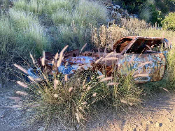 Rustykalny porzucony samochód w górach przeciwko błękitnemu niebu — Zdjęcie stockowe