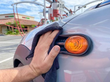 Mans el temizliği siyah mikrofiber bez ile araba. Arabanın yüzeyi elle silinmiş.