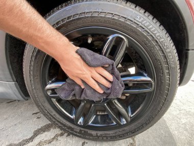 Mans el temizliği siyah mikrofiber bez ile araba. Arabanın yüzeyi elle silinmiş.