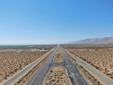 Kaliforniya Mojave Çölü 'nde, Ridgecrest yakınlarındaki mavi gökyüzünün altında çölün ortasındaki yol manzarası.. 