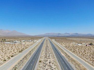 Kaliforniya Mojave Çölü 'nde, Ridgecrest yakınlarındaki mavi gökyüzünün altında çölün ortasındaki yol manzarası.. 