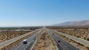 Kaliforniya çölünde mavi gökyüzünün altında çölün ortasındaki yol manzarası.