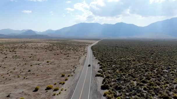 ほこりだらけの乾燥砂漠の土地の真ん中のアスファルト道路上の車の運転の空中ビュー — ストック動画