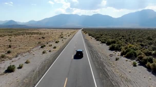 먼지투성이의 건조 한 사막 지대의 아스팔트 길에서 차를 몰고 가는 모습을 공중에서 본 모습 — 비디오