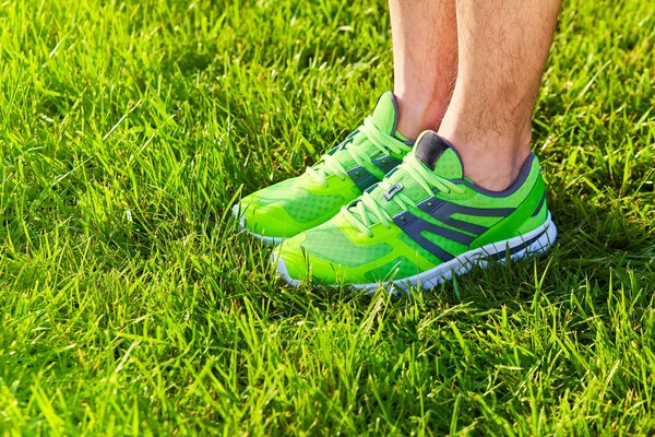 Spor ayakkabı ayakkabı taze yeşil çim alan. Spor ekipmanları alt görünümü. Açık havada spor.