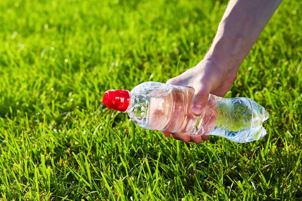 手持一瓶纯净水对绿色模糊的草背景 — 图库照片