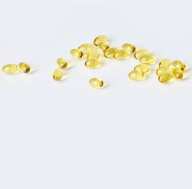 Fish oil capsules on white background.  Healthcare concept.  Scattered supplements.  Space for text.  Horizontal