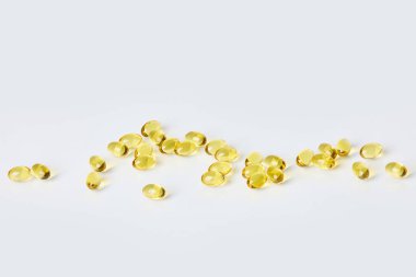 Fish oil capsules on white background.  Healthcare concept.  Scattered supplements.  Space for text.  Horizontal