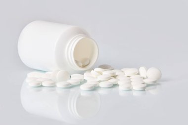 Tabletler ve hapları beyaz ayna arka plan üzerinde beyaz. Sağlık kavramı. Plastik şişe dağınık takviyeleri