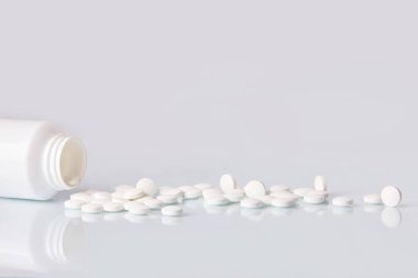 Tabletler ve hapları beyaz ayna arka plan üzerinde beyaz. Sağlık kavramı. Plastik şişe dağınık takviyeleri